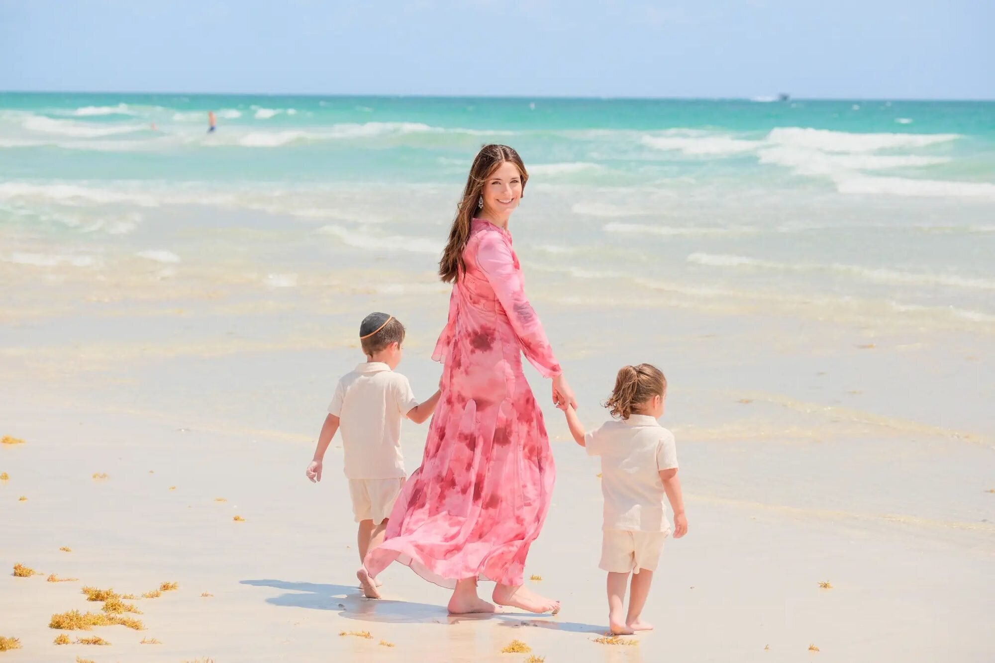 Miami Family Photographer | South Beach Session A mother walking hand in hand with her two young children along the turquoise shoreline at South Beach, Miami — captured by a Dreamgraphy Miami family photographer