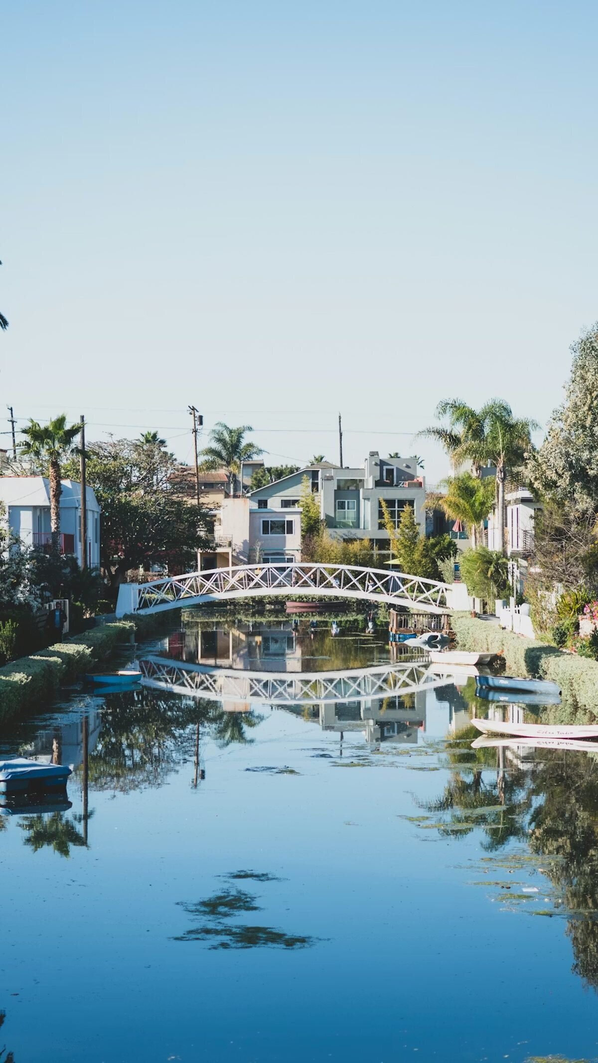 White arched bridge reflected in the still water of the Venice Canals in Los Angeles, a charming location for engagement photos