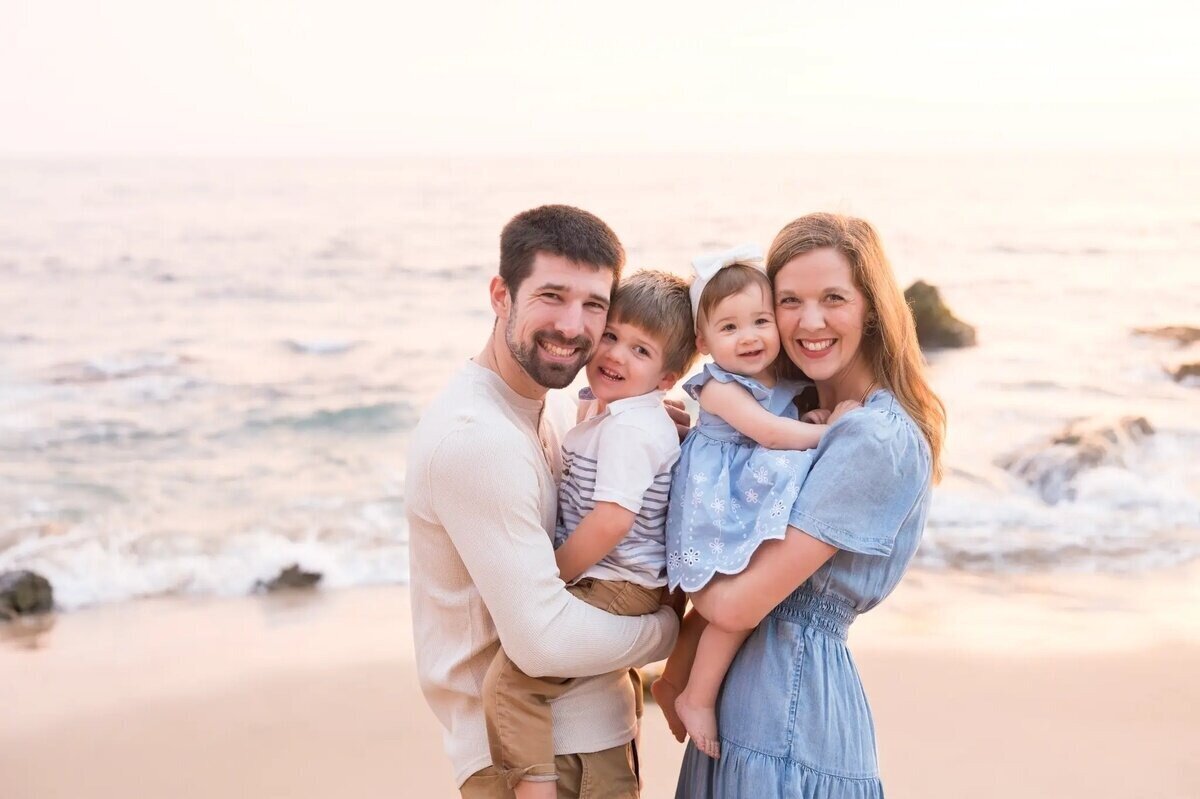 A family of four laughing together naturally during an outdoor photoshoot