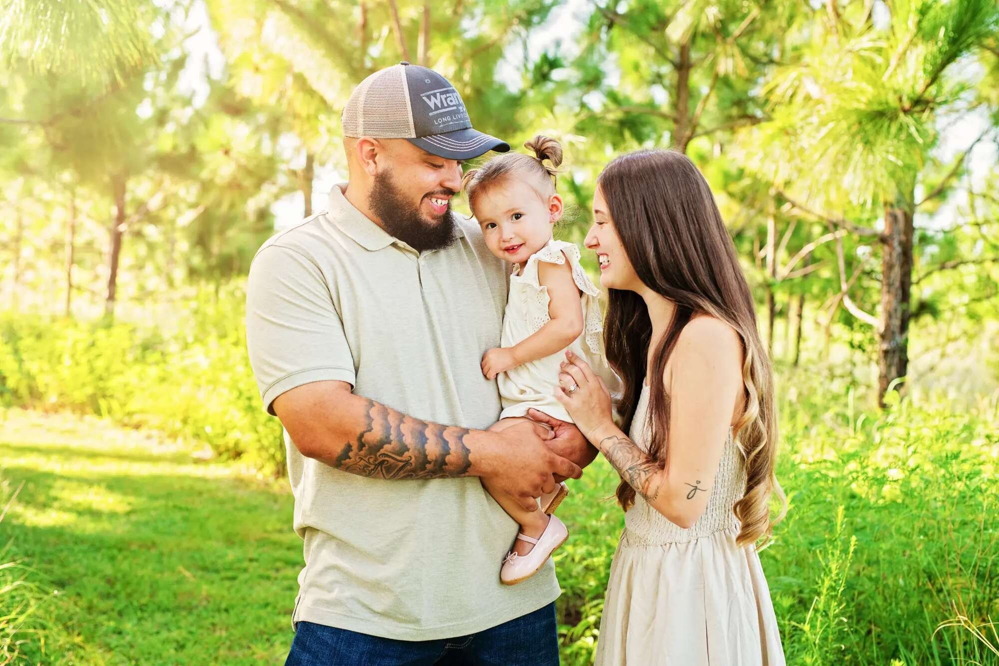 Orlando family photographer capturing a family of three sitting together in a lush Florida pine forest park