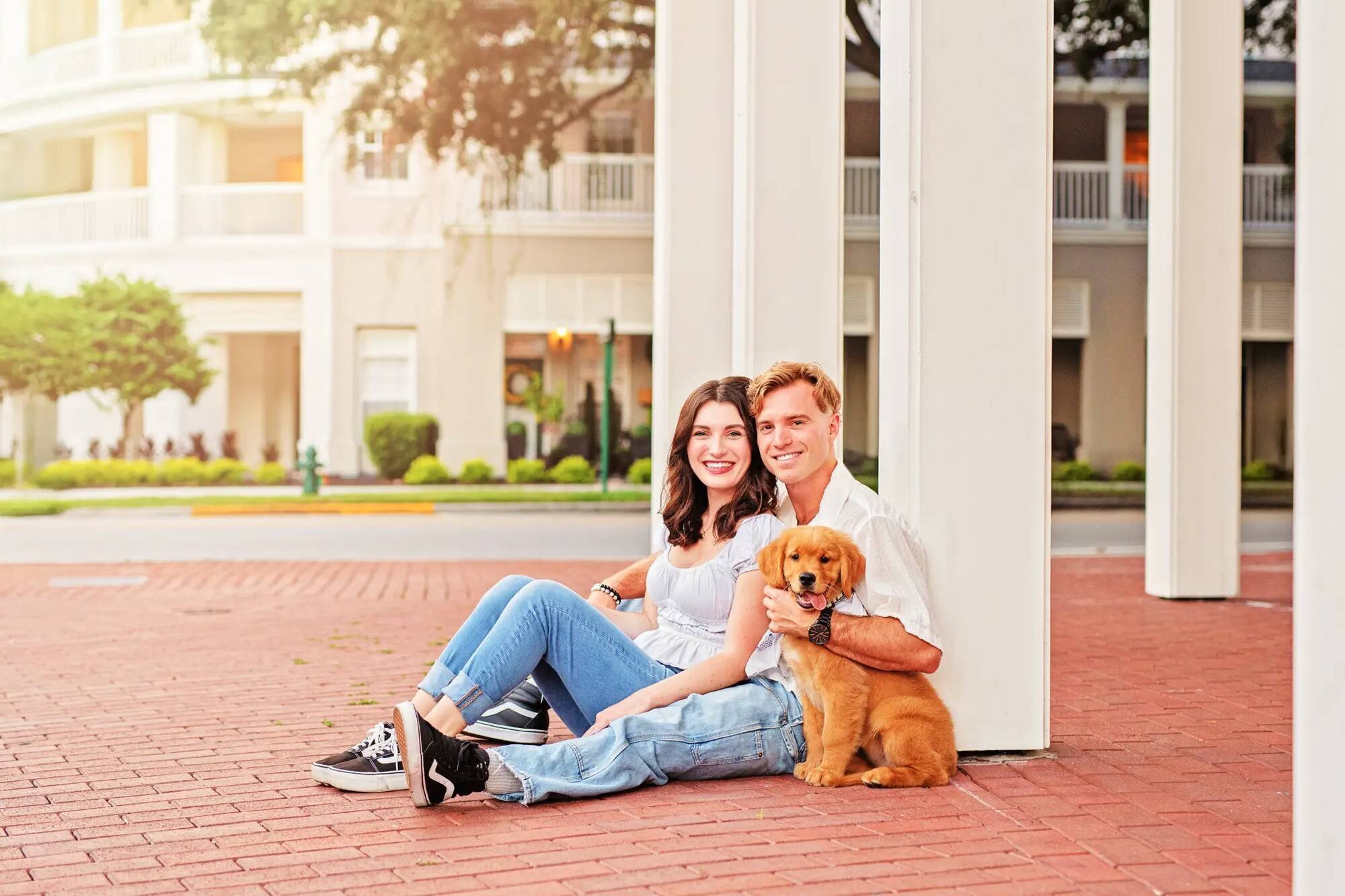 Orlando couples photographer capturing a young couple sitting with their golden retriever puppy outside a Disney resort hotel
