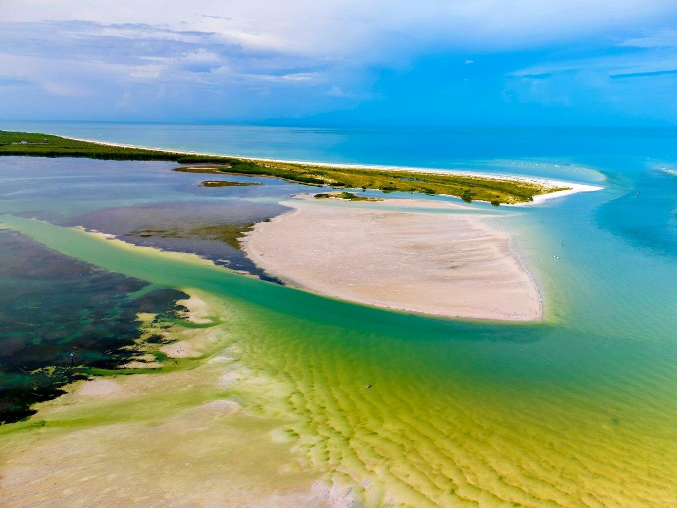 Aerial view of Caladesi Island State Park in Dunedin, Florida, showing the pristine white sandbar surrounded by turquoise and emerald Gulf waters — a secluded Tampa photo session location by Dreamgraphy