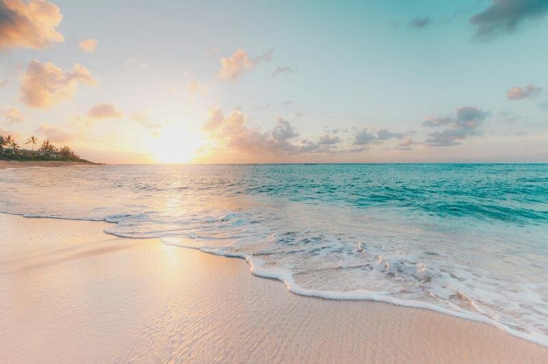A golden sunset over the calm Gulf waters at St. Pete Beach, Florida, with soft pink and orange skies reflecting on the water — a popular Tampa photo session location by Dreamgraphy