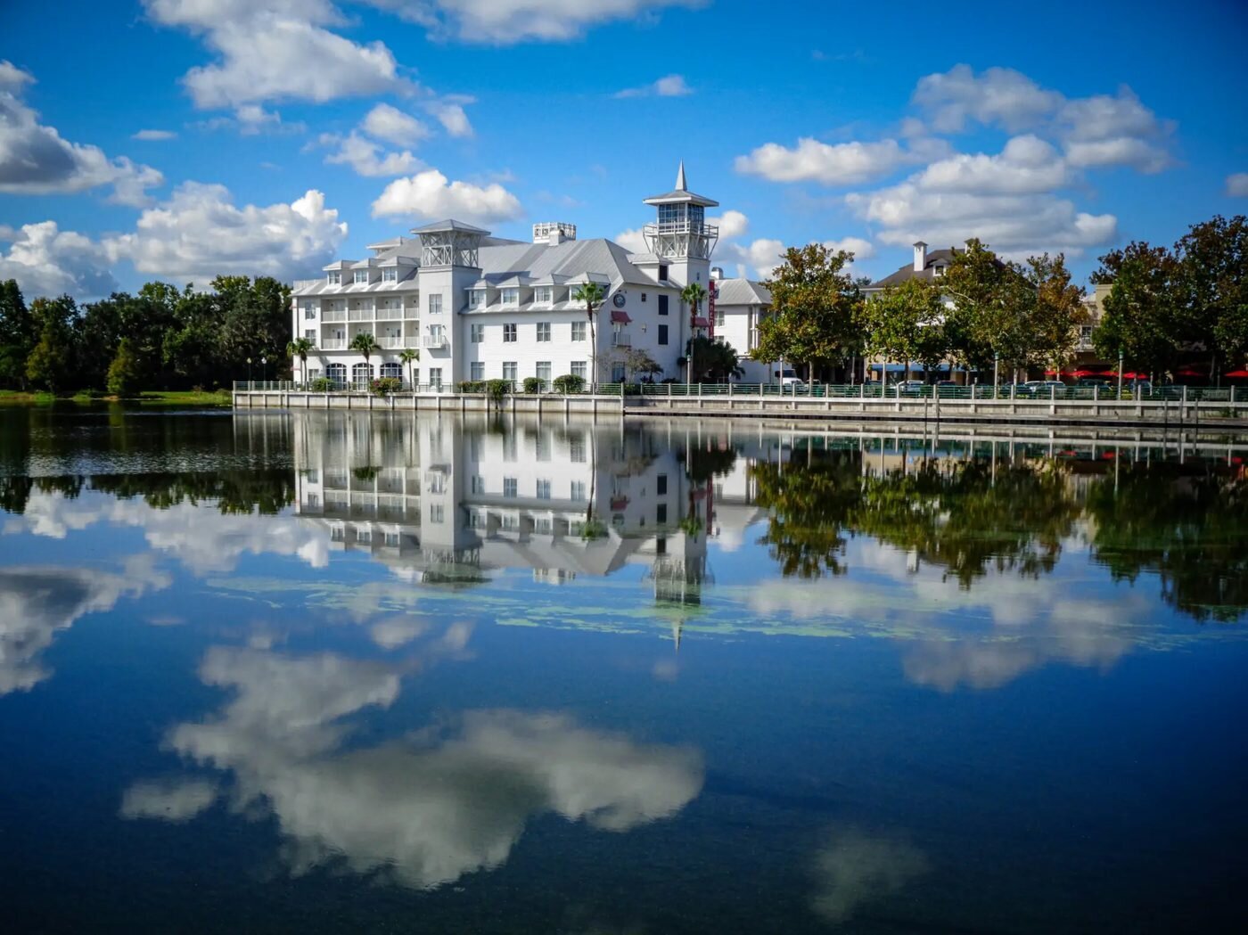 Lakefront view of classic white architecture reflected in calm water in Celebration Florida, a charming engagement photo location near Orlando