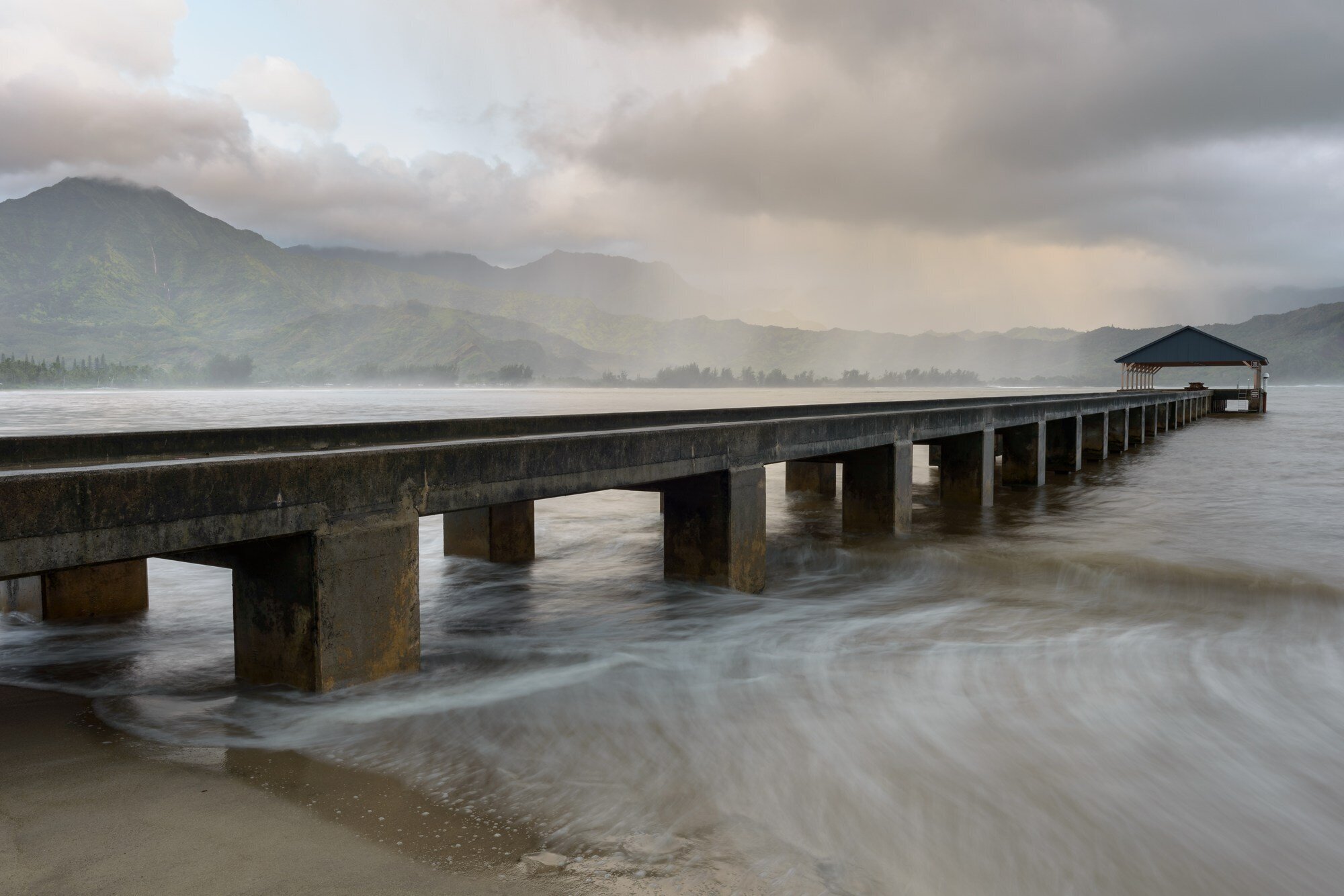 Hanalei Pier stretching into Hanalei Bay on Kauai's North Shore, with dramatic mountain backdrop