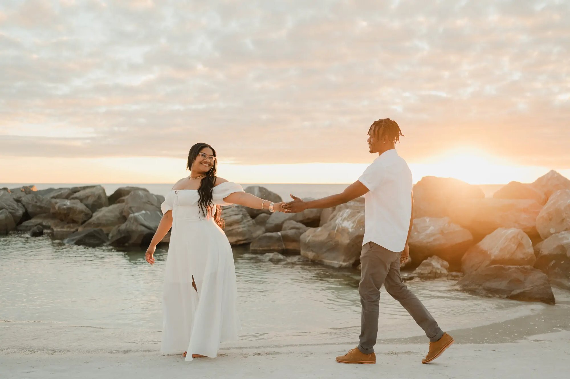 Orlando couples photographer capturing a couple reaching for each other's hands on a Florida beach during a golden sunset
