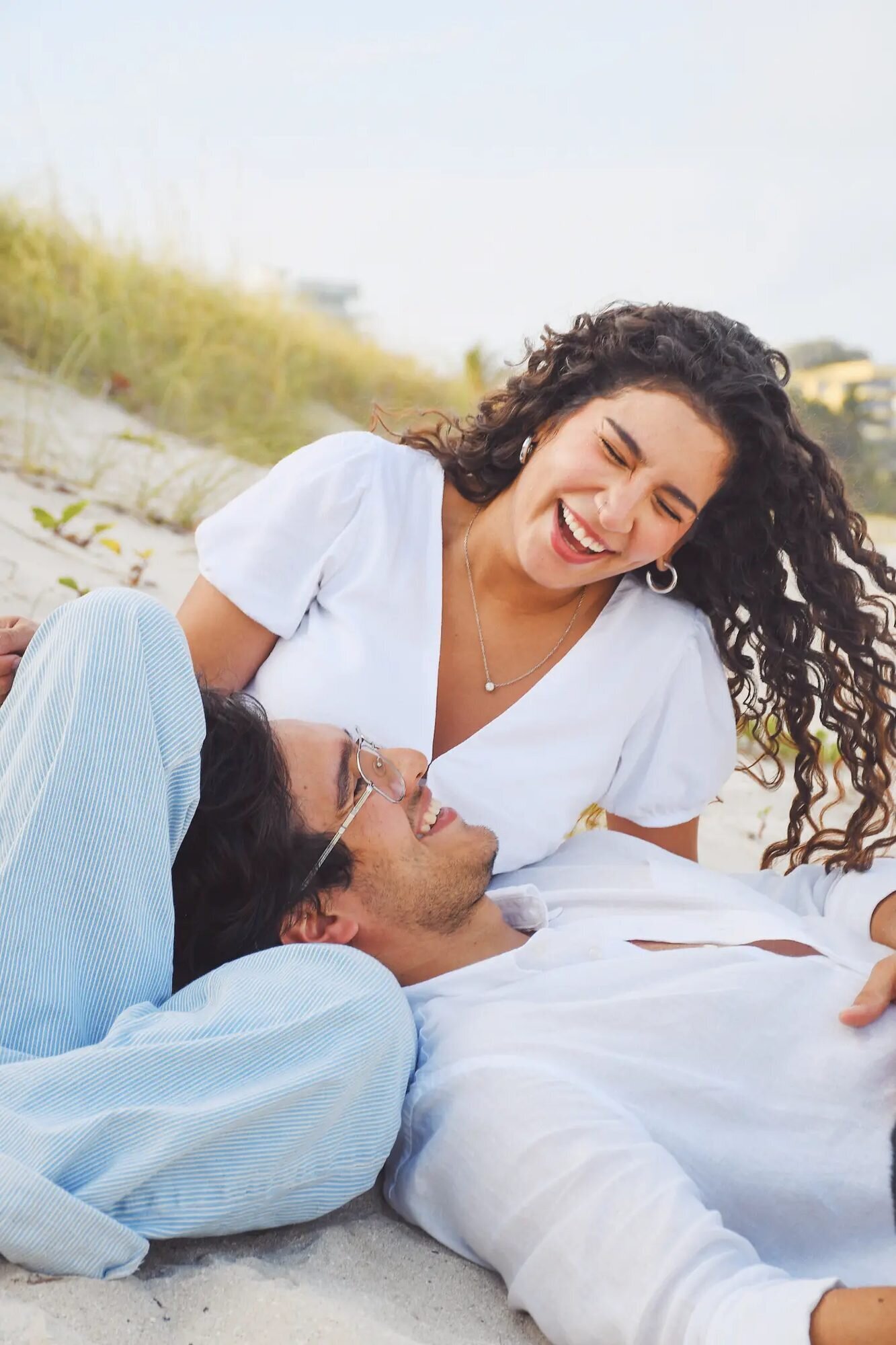 Miami Couple Photographer | South Beach Session A couple laughing together on the sand at South Beach, Miami — captured by a Dreamgraphy Miami couple photographer