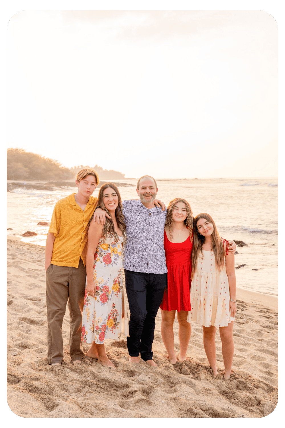 Family of four posing together on a sandy beach during a vacation family photoshoot with Dreamgraphy