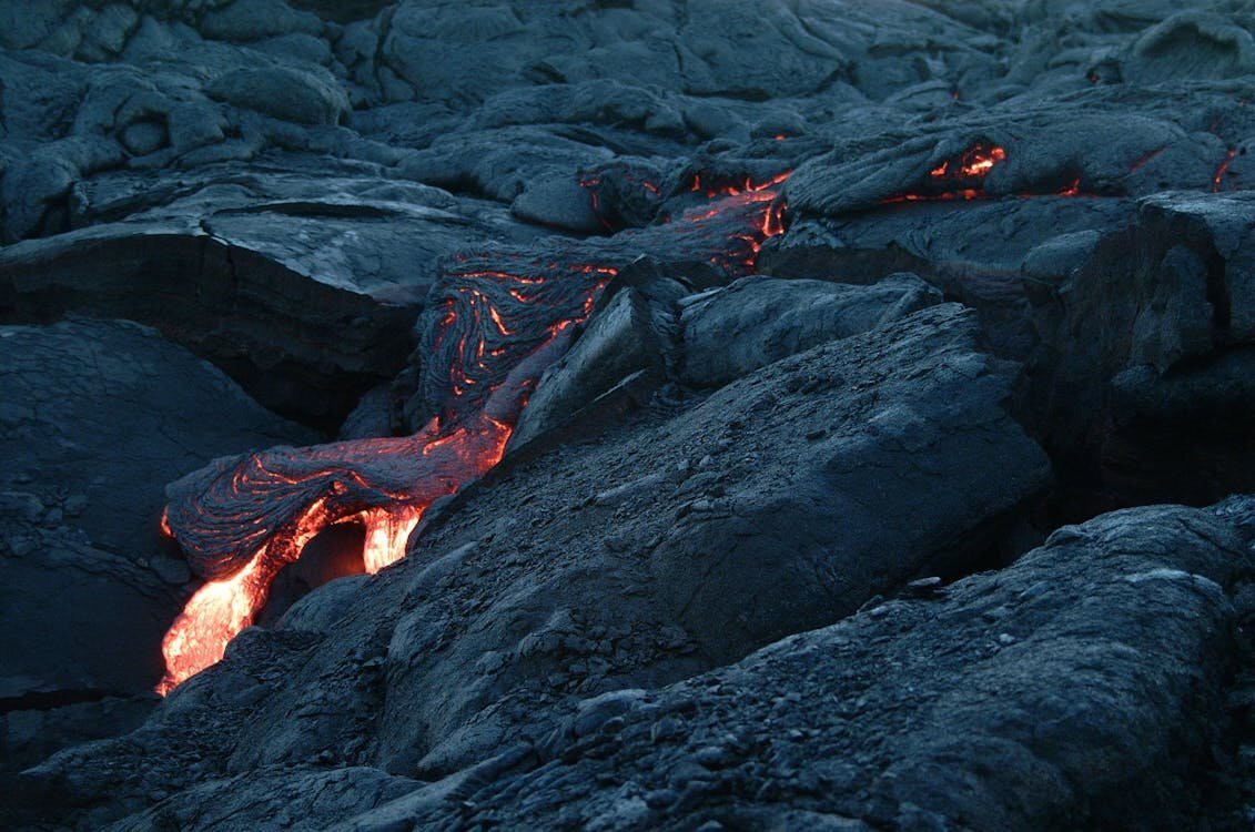 Glowing lava flow over dark volcanic rock at Hawaii Volcanoes National Park on the Big Island of Hawaii