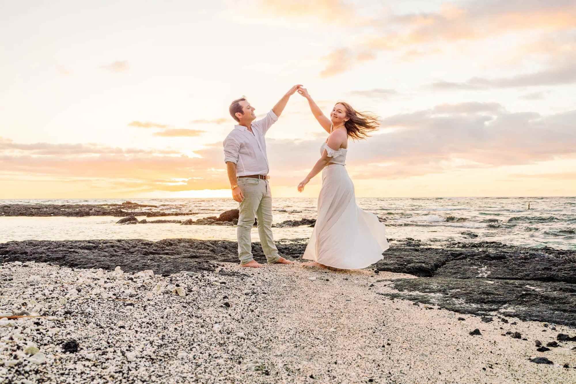 A couple dancing together on a rocky beach at golden hour during a romantic couple photoshoot