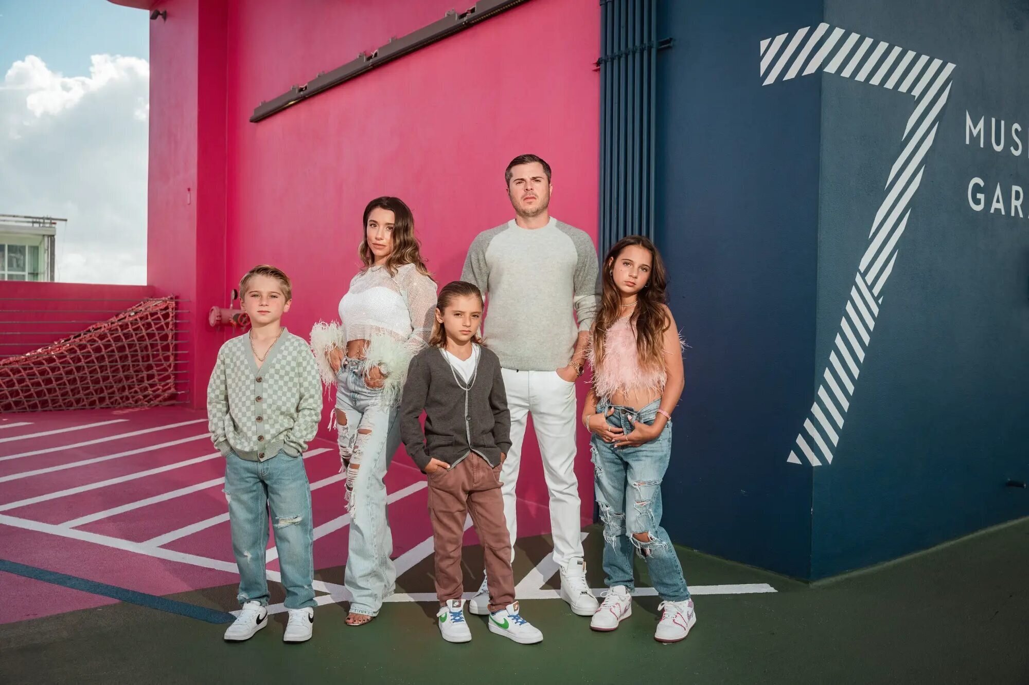 A family of 5 posing for their family session at Museum Garage District in Miami with colorful background. 