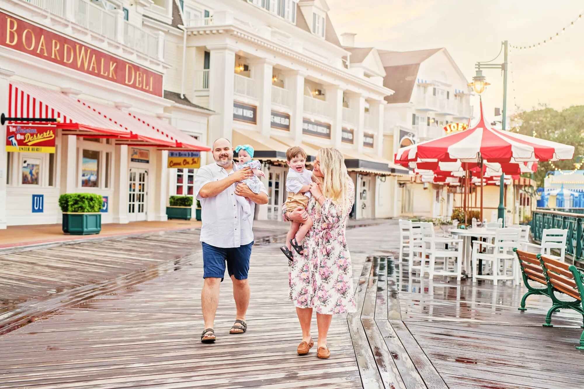 Orlando family photographer capturing a family of four with two young children walking along the Disney Boardwalk Resort promenade