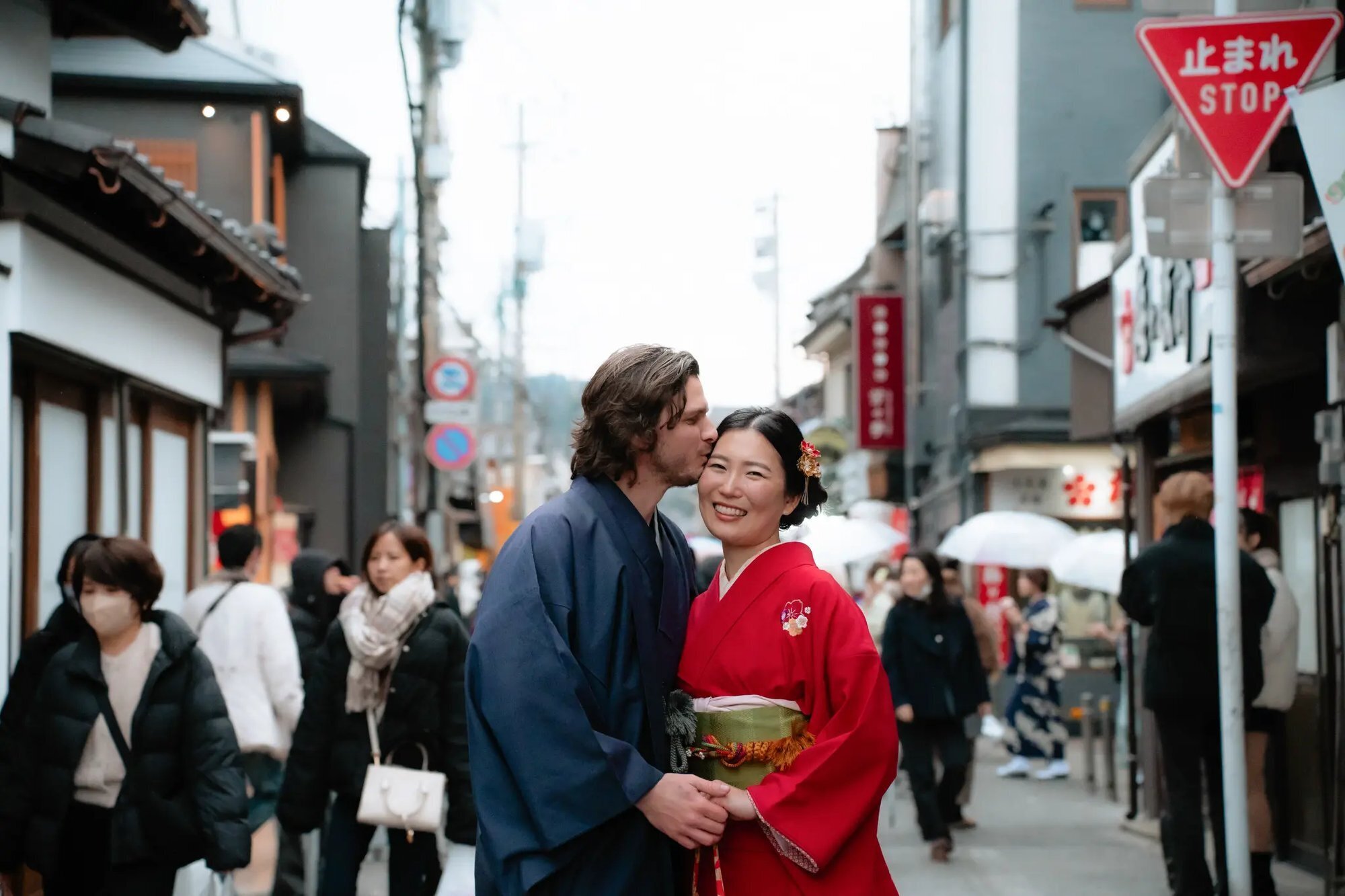 A couple dressed in traditional Japanese kimono embracing on a busy street in Hakata, Fukuoka, during a professional couples photo session