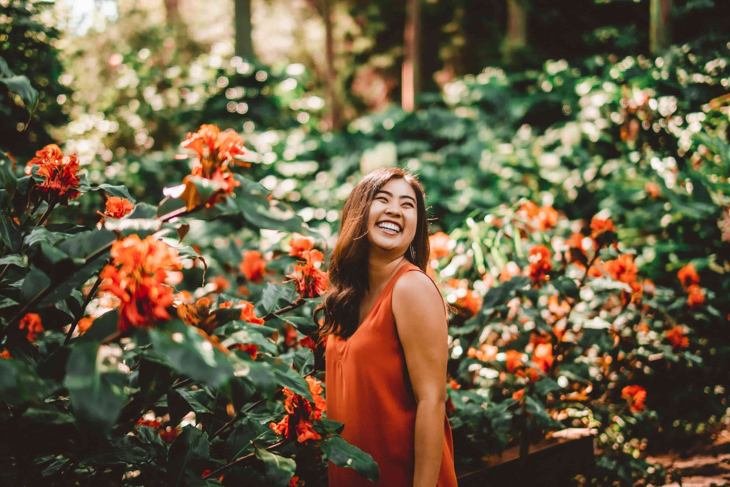 Maui photographer — woman laughing in tropical garden with orange flowers
