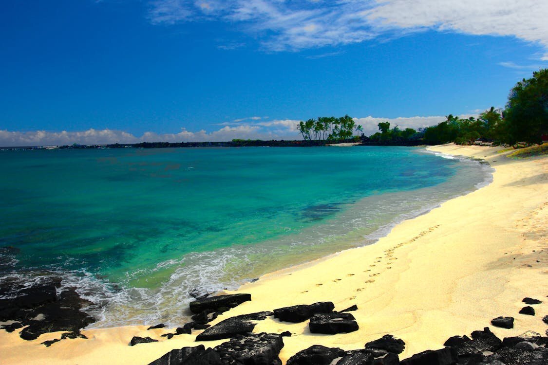 Clear turquoise water and white sand beach with lava rocks along the Kohala Coast on the Big Island of Hawaii
