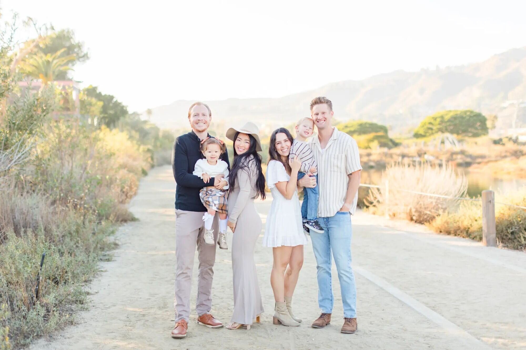 Two young families posing together on a sandy trail at Malibu Creek State Park during a golden hour session with a Los Angeles family photographer